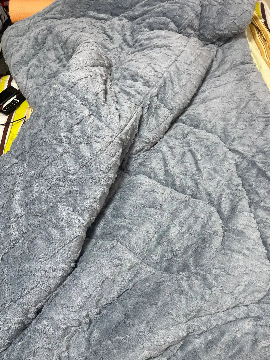 Une couverture moelleuse en patchwork gris avec une surface douce et texturée.