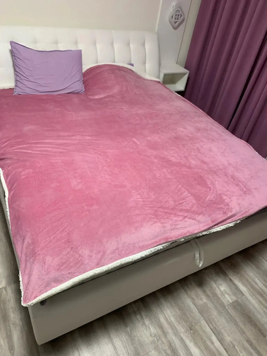 Couverture en peluche rose avec une bordure en polaire blanche.