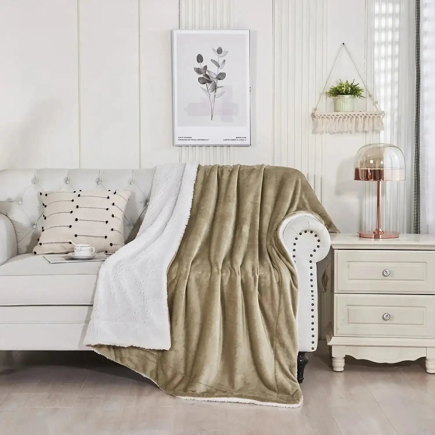 Une couverture en sherpa vert olive et blanc moelleuse drapée sur un canapé capitonné.